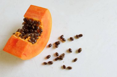 Üst ve düz taze, olgun bir papaya meyvesi uzanıyor. Tohumları, yemek dokusunu, kesimini, kesilmiş meyveleri beyaz bir zeminde izole edilmiş. Sağlıklı beslenme için sebze ve meyve.