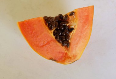 Üst ve düz taze, olgun bir papaya meyvesi uzanıyor. Tohumları, yemek dokusunu, kesimini, kesilmiş meyveleri beyaz bir zeminde izole edilmiş. Sağlıklı beslenme için sebze ve meyve.