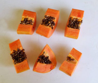 Üst ve düz taze, olgun bir papaya meyvesi uzanıyor. Tohumları, yemek dokusunu, kesimini, kesilmiş meyveleri beyaz bir zeminde izole edilmiş. Sağlıklı beslenme için sebze ve meyve.