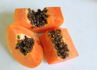 Üst ve düz taze, olgun bir papaya meyvesi uzanıyor. Tohumları, yemek dokusunu, kesimini, kesilmiş meyveleri beyaz bir zeminde izole edilmiş. Sağlıklı beslenme için sebze ve meyve.
