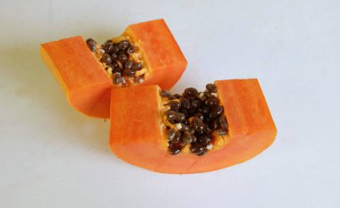 Üst ve düz taze, olgun bir papaya meyvesi uzanıyor. Tohumları, yemek dokusunu, kesimini, kesilmiş meyveleri beyaz bir zeminde izole edilmiş. Sağlıklı beslenme için sebze ve meyve.