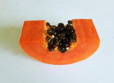 Üst ve düz taze, olgun bir papaya meyvesi uzanıyor. Tohumları, yemek dokusunu, kesimini, kesilmiş meyveleri beyaz bir zeminde izole edilmiş. Sağlıklı beslenme için sebze ve meyve.