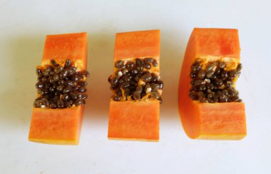 Üst ve düz taze, olgun bir papaya meyvesi uzanıyor. Tohumları, yemek dokusunu, kesimini, kesilmiş meyveleri beyaz bir zeminde izole edilmiş. Sağlıklı beslenme için sebze ve meyve.