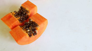 Üst ve düz taze, olgun bir papaya meyvesi uzanıyor. Tohumları, yemek dokusunu, kesimini, kesilmiş meyveleri beyaz bir zeminde izole edilmiş. Sağlıklı beslenme için sebze ve meyve.