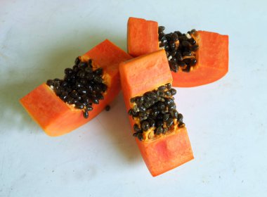 Üst ve düz taze, olgun bir papaya meyvesi uzanıyor. Tohumları, yemek dokusunu, kesimini, kesilmiş meyveleri beyaz bir zeminde izole edilmiş. Sağlıklı beslenme için sebze ve meyve.
