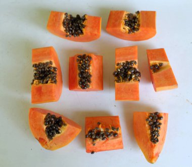Üst ve düz taze, olgun bir papaya meyvesi uzanıyor. Tohumları, yemek dokusunu, kesimini, kesilmiş meyveleri beyaz bir zeminde izole edilmiş. Sağlıklı beslenme için sebze ve meyve.