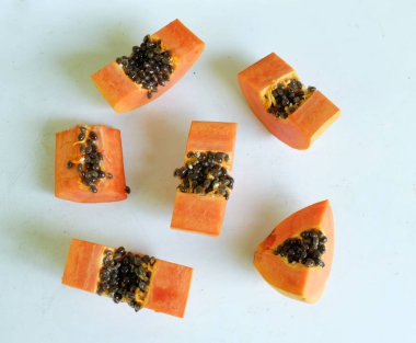 Üst ve düz taze, olgun bir papaya meyvesi uzanıyor. Tohumları, yemek dokusunu, kesimini, kesilmiş meyveleri beyaz bir zeminde izole edilmiş. Sağlıklı beslenme için sebze ve meyve.