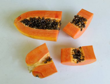 Üst ve düz taze, olgun bir papaya meyvesi uzanıyor. Tohumları, yemek dokusunu, kesimini, kesilmiş meyveleri beyaz bir zeminde izole edilmiş. Sağlıklı beslenme için sebze ve meyve.