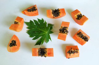 Üst ve düz taze, olgun bir papaya meyvesi uzanıyor. Tohumları, yemek dokusunu, kesimini, kesilmiş meyveleri beyaz bir zeminde izole edilmiş. Sağlıklı beslenme için sebze ve meyve.