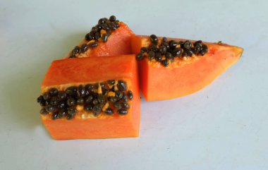 Üst ve düz taze, olgun bir papaya meyvesi uzanıyor. Tohumları, yemek dokusunu, kesimini, kesilmiş meyveleri beyaz bir zeminde izole edilmiş. Sağlıklı beslenme için sebze ve meyve.