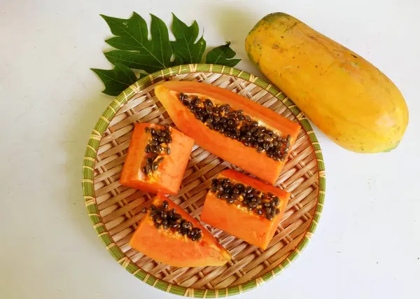 Üst ve düz taze, olgun bir papaya meyvesi uzanıyor tohumlarla, yemek dokusuyla, kesilmiş, dilimlenmiş meyveler ahşap tepside izole edilmiş. Sağlıklı beslenme için sebze ve meyve