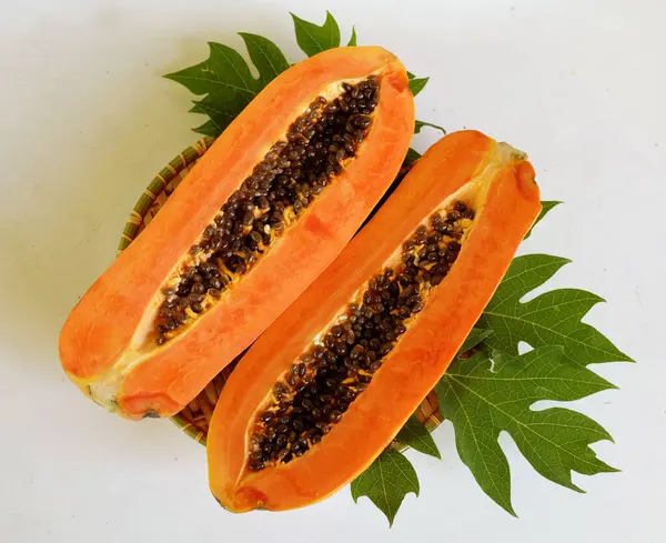 Üst ve düz taze, olgun bir papaya meyvesi uzanıyor tohumlarla, yemek dokusuyla, kesilmiş, dilimlenmiş meyveler ahşap tepside izole edilmiş. Sağlıklı beslenme için sebze ve meyve