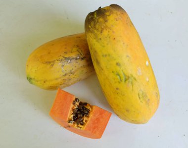 Üst ve düz taze, olgun bir papaya meyvesi uzanıyor. Tohumları, yemek dokusunu, kesimini, kesilmiş meyveleri beyaz bir zeminde izole edilmiş. Sağlıklı beslenme için sebze ve meyve