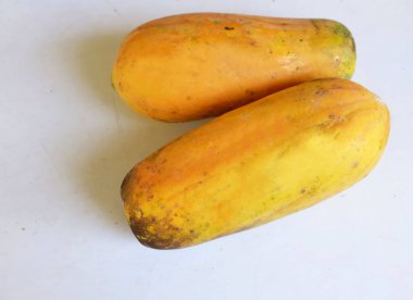 Üst ve düz taze, olgun bir papaya meyvesi uzanıyor. Tohumları, yemek dokusunu, kesimini, kesilmiş meyveleri beyaz bir zeminde izole edilmiş. Sağlıklı beslenme için sebze ve meyve