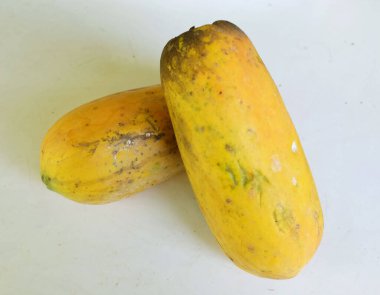 Üst ve düz taze, olgun bir papaya meyvesi uzanıyor. Tohumları, yemek dokusunu, kesimini, kesilmiş meyveleri beyaz bir zeminde izole edilmiş. Sağlıklı beslenme için sebze ve meyve