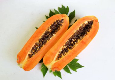 Üst ve düz taze, olgun bir papaya meyvesi uzanıyor. Tohumları, yemek dokusunu, kesimini, kesilmiş meyveleri beyaz bir zeminde izole edilmiş. Sağlıklı beslenme için sebze ve meyve