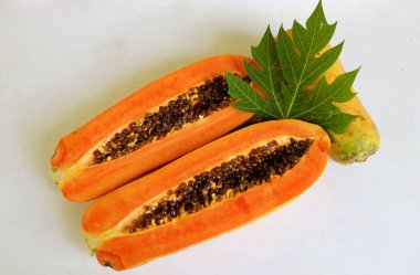 Üst ve düz taze, olgun bir papaya meyvesi uzanıyor. Tohumları, yemek dokusunu, kesimini, kesilmiş meyveleri beyaz bir zeminde izole edilmiş. Sağlıklı beslenme için sebze ve meyve