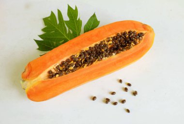 Üst ve düz taze, olgun bir papaya meyvesi uzanıyor. Tohumları, yemek dokusunu, kesimini, kesilmiş meyveleri beyaz bir zeminde izole edilmiş. Sağlıklı beslenme için sebze ve meyve