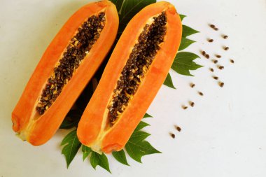 Üst ve düz taze, olgun bir papaya meyvesi uzanıyor. Tohumları, yemek dokusunu, kesimini, kesilmiş meyveleri beyaz bir zeminde izole edilmiş. Sağlıklı beslenme için sebze ve meyve