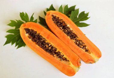 Üst ve düz taze, olgun bir papaya meyvesi uzanıyor. Tohumları, yemek dokusunu, kesimini, kesilmiş meyveleri beyaz bir zeminde izole edilmiş. Sağlıklı beslenme için sebze ve meyve