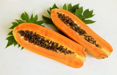 Üst ve düz taze, olgun bir papaya meyvesi uzanıyor. Tohumları, yemek dokusunu, kesimini, kesilmiş meyveleri beyaz bir zeminde izole edilmiş. Sağlıklı beslenme için sebze ve meyve