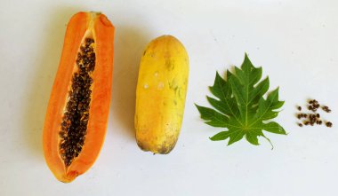 Üst ve düz taze, olgun bir papaya meyvesi uzanıyor. Tohumları, yemek dokusunu, kesimini, kesilmiş meyveleri beyaz bir zeminde izole edilmiş. Sağlıklı beslenme için sebze ve meyve