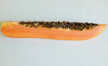 Üst ve düz taze, olgun bir papaya meyvesi uzanıyor. Tohumları, yemek dokusunu, kesimini, kesilmiş meyveleri beyaz bir zeminde izole edilmiş. Sağlıklı beslenme için sebze ve meyve