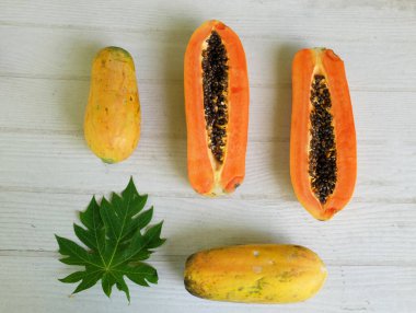 Üst ve düz bir şekilde olgun papaya meyveli papaya, yeşil yapraklı, yalıtılmış beyaz ahşap arka plan. Sağlıklı beslenme için sebze ve meyve.