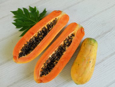 Üst ve düz bir şekilde olgun papaya meyveli papaya, yeşil yapraklı, yalıtılmış beyaz ahşap arka plan. Sağlıklı beslenme için sebze ve meyve.