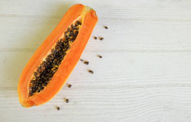 Üst ve düz bir şekilde olgun papaya meyveli papaya, yeşil yapraklı, yalıtılmış beyaz ahşap arka plan. Sağlıklı beslenme için sebze ve meyve.
