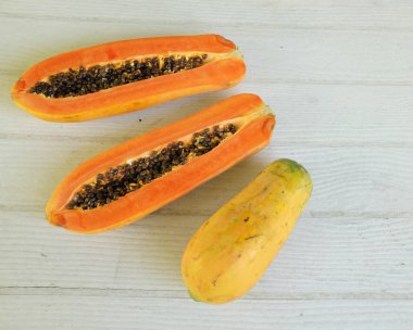 Üst ve düz bir şekilde olgun papaya meyveli papaya, yeşil yapraklı, yalıtılmış beyaz ahşap arka plan. Sağlıklı beslenme için sebze ve meyve.