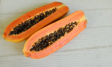 Üst ve düz bir şekilde olgun papaya meyveli papaya, yeşil yapraklı, yalıtılmış beyaz ahşap arka plan. Sağlıklı beslenme için sebze ve meyve.