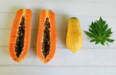 Üst ve düz bir şekilde olgun papaya meyveli papaya, yeşil yapraklı, yalıtılmış beyaz ahşap arka plan. Sağlıklı beslenme için sebze ve meyve.
