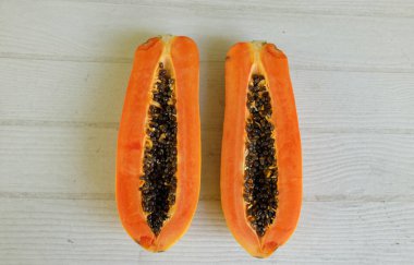 Üst ve düz bir şekilde olgun papaya meyveli papaya, yeşil yapraklı, yalıtılmış beyaz ahşap arka plan. Sağlıklı beslenme için sebze ve meyve.