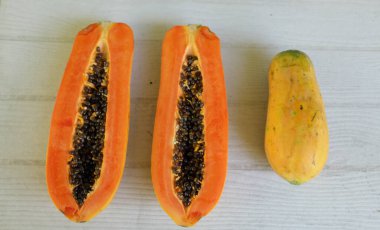 Üst ve düz bir şekilde olgun papaya meyveli papaya, yeşil yapraklı, yalıtılmış beyaz ahşap arka plan. Sağlıklı beslenme için sebze ve meyve.