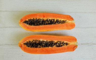 Üst ve düz bir şekilde olgun papaya meyveli papaya, yeşil yapraklı, yalıtılmış beyaz ahşap arka plan. Sağlıklı beslenme için sebze ve meyve.