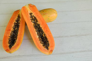 Üst ve düz bir şekilde olgun papaya meyveli papaya, yeşil yapraklı, yalıtılmış beyaz ahşap arka plan. Sağlıklı beslenme için sebze ve meyve.