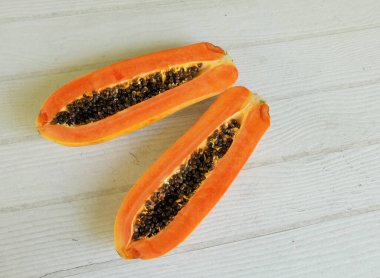 Üst ve düz bir şekilde olgun papaya meyveli papaya, yeşil yapraklı, yalıtılmış beyaz ahşap arka plan. Sağlıklı beslenme için sebze ve meyve.
