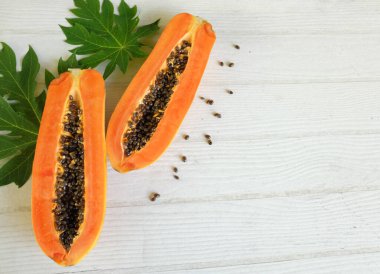 Üst ve düz bir şekilde olgun papaya meyveli papaya, yeşil yapraklı, yalıtılmış beyaz ahşap arka plan. Sağlıklı beslenme için sebze ve meyve.