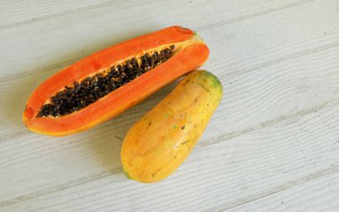 Üst ve düz bir şekilde olgun papaya meyveli papaya, yeşil yapraklı, yalıtılmış beyaz ahşap arka plan. Sağlıklı beslenme için sebze ve meyve.