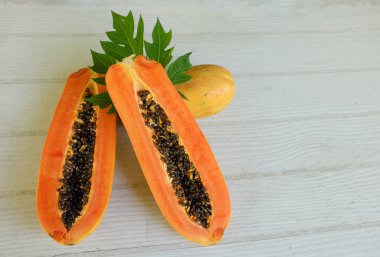 Üst ve düz bir şekilde olgun papaya meyveli papaya, yeşil yapraklı, yalıtılmış beyaz ahşap arka plan. Sağlıklı beslenme için sebze ve meyve.
