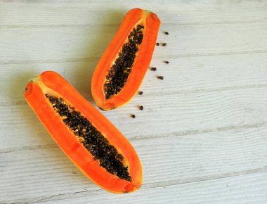Üst ve düz bir şekilde olgun papaya meyveli papaya, yeşil yapraklı, yalıtılmış beyaz ahşap arka plan. Sağlıklı beslenme için sebze ve meyve.