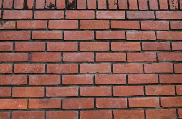 Turuncu duvara kırmızı boya sıçramış, kırmızı taş blokların zemini, eski tuğla duvarın arka planı, eski tuğla evin arka planı, kırmızı tuğla arka plan dokusu ve deseni. Tasarım için boş alan 