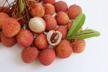 Yığınla taze taze, sulu kırmızı liçi, litçi, liçi meyveleri (litchi chinensis sonn). Tüm liçi ve ikiye bölünmüş yeşil yaprak beyaz bir zemin üzerinde izole edilmiş.