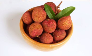 Taze taze tatlı sulu kırmızı liçi, litçi, liçi meyveleri (litchi chinensis sonn.) Tüm liçi ve ikiye bölünmüş yeşil bir yaprak, ahşap bir kasede beyaz bir zemin üzerinde izole edilmiş.