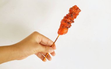 appetizing a chicken butt grilled ,chicken grilled skewered on bamboo In the hands of an Asian woman  isolate on a white backdrop . halal food, street food in thailand