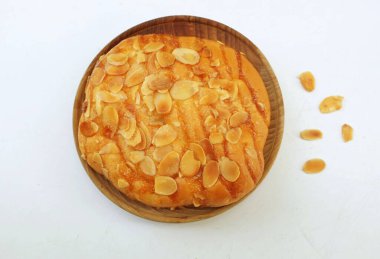 Lezzetli, tatlı ve sulu ev yapımı hamur işi. Dilimlenmiş badem ve şeker jöleli taze ekmek rulosu. Tahta tabakta badem ezmeli çörek.