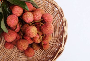 Taze taze tatlı sulu kırmızı liçi, litçi, liçi meyveleri (litchi chinensis sonn.) Bambu sepetinde yeşil bir yaprak, beyaz bir zemin üzerinde izole edilmiş bir yaprak.