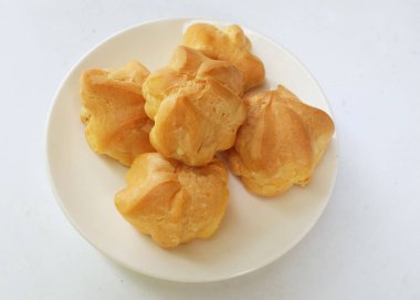 Üstten bakıldığında taze ev yapımı pasta, taze pişmiş kremalı pasta, choux kreması, profiterol beyaz arka planda izole edilmiş tabakta.