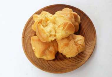 Üstten bakıldığında taze ev yapımı pasta, taze pişmiş kremalı pasta, choux kreması, profiterol kahverengi ahşap tabakta beyaz arka planda izole edilmiş.